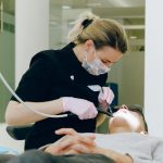 Female dentist performing a dental check-up and treatment on a patient in a modern dental clinic